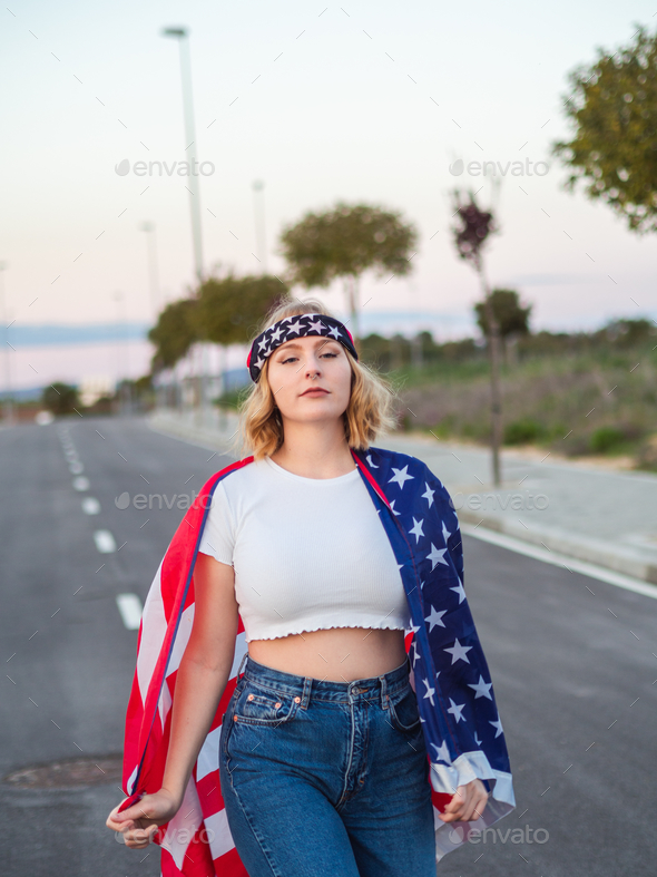 Vertical shot of a blonde Caucasian woman from Spain wearing the American flag and headband