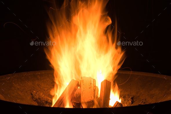 Closeup shot of a fire in black round fire pit during nighttime