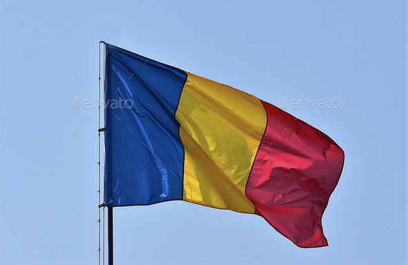 Flag of Romania with blue, yellow, red vertical lines in the blue sky ...