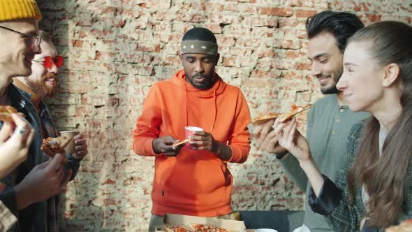 Cheerful Men and Women Enjoying Pizza and Carefree Conversation in Modern Shared Office alt