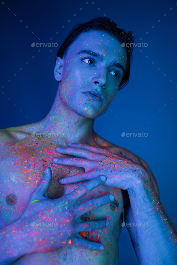 good looking and athletic shirtless man posing in radiant and colorful neon  body paint and touching Stock Photo by LightFieldStudios