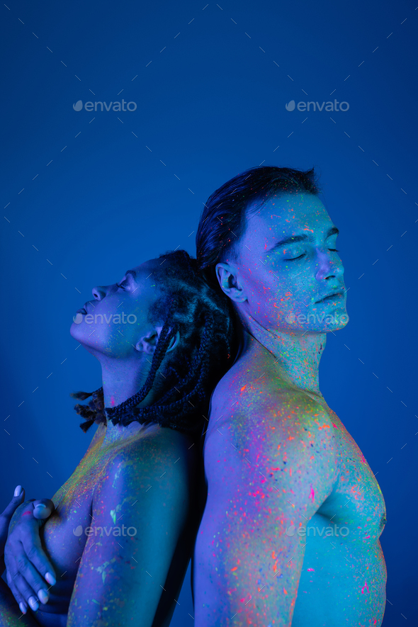 young interracial couple in colorful neon body paint standing back
