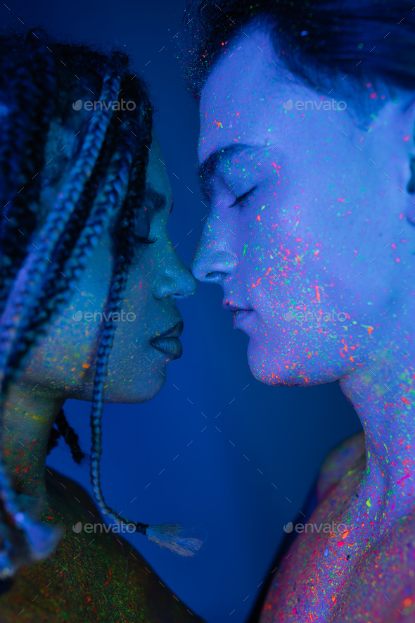 young interracial couple in colorful neon body paint standing back