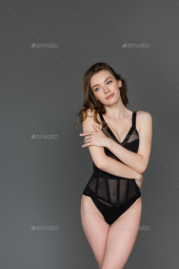 Sexy brunette woman with natural makeup, slim body and hairstyle posing in  stylish black bodysuit Stock Photo by LightFieldStudios