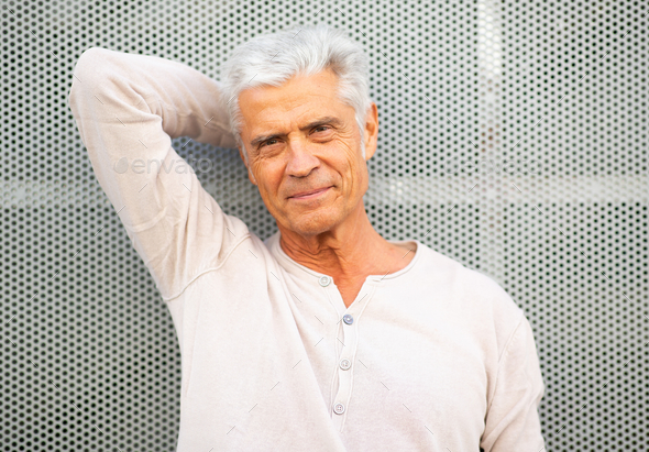 handsome older man leaning against wall with hand behind head Stock ...