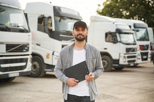 Black colored notepad in hands. Young truck driver in casual clothes