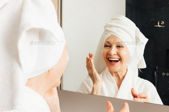 Woman Wrapped with Bath Towels, Applying Cream on her Face Stock