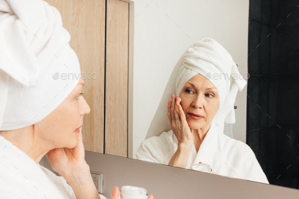 Woman Wrapped with Bath Towels, Applying Cream on her Face Stock