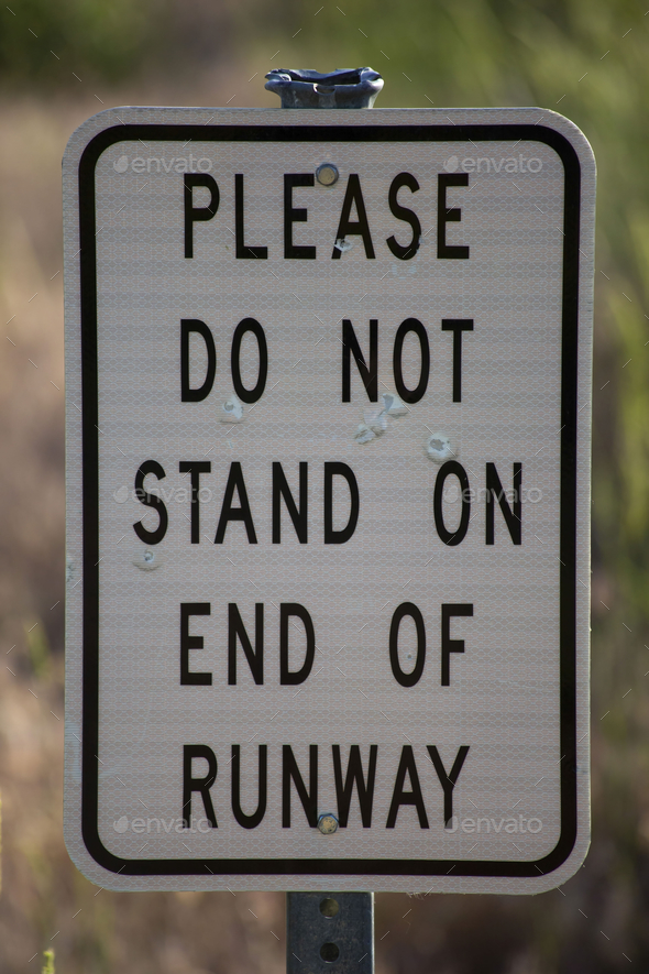 Shot of the sign asking not to stand on the end of the runway written in white with black.