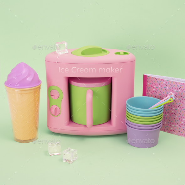 Closeup of pastel-colored ice cream maker with other kitchen equipment on a pastel green background