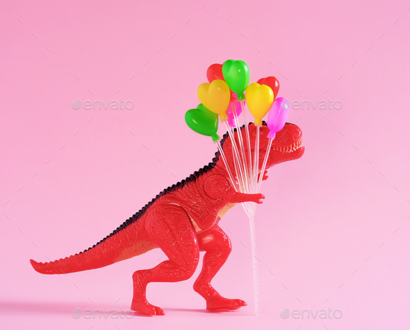 Red dinosaur holding colorful balloons on pink background.