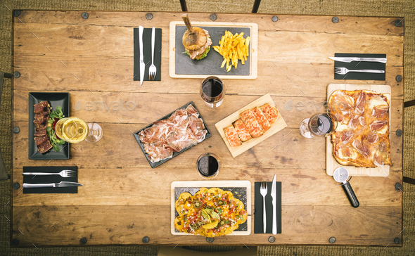 Zenith view of rustic table with different food dishes and glasses of wine
