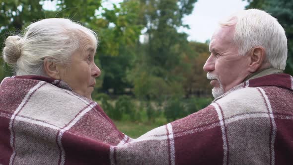 Surprised Senior Woman Looking at Husband Telling Her Gossips, Couple Under Rug