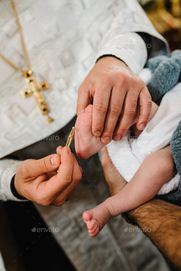 Baptism ceremony of a baby. Close up of tiny baby feet, the sacrament of baptism. The godfather hold