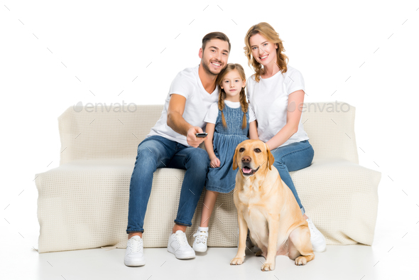 smiling family with dog watching tv on sofa, isolated on white