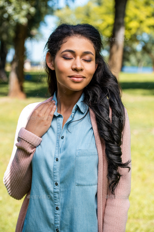 Attractive African American Woman Posing With Closed Eyes In Park Stock