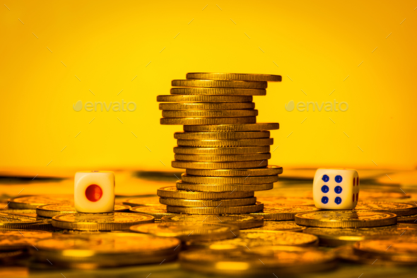 Closeup of dice near a stack of coins against a golden background - concept of gambling