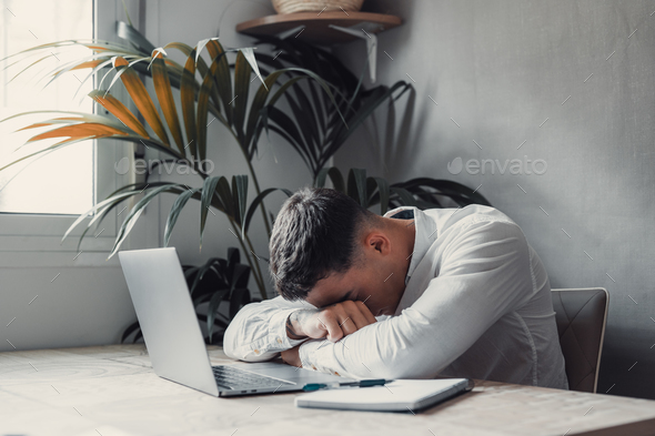 Exhausted young Caucasian male employee sleep desk at office overwork