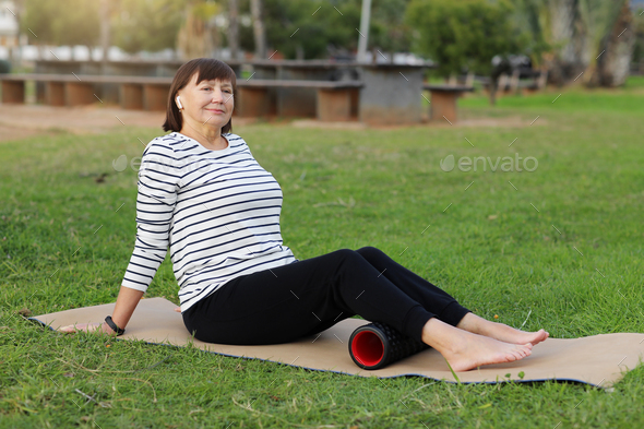 Relaxation after workout. Happy adult sportive woman in casual sportswear works out the fascia of