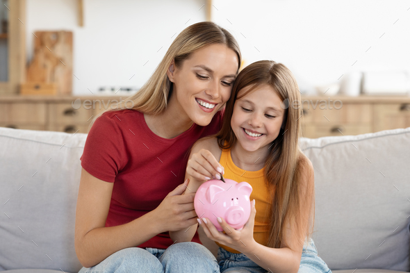 Friendly mom and kid thrift coins in piggybank, home interior