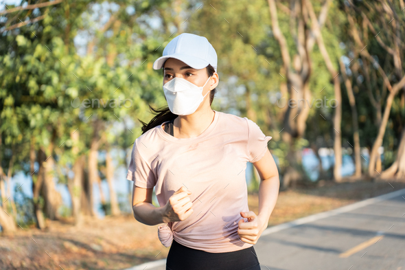 Asian young active sport woman wear mask run on street in public park.