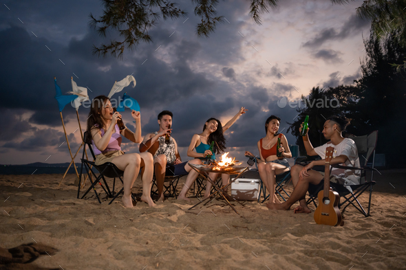 Group of Asian young man and woman having party on the beach at night.