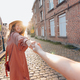 follow me concept - happy smiling woman holding hand of girlfriend in old downtown street - PhotoDune Item for Sale