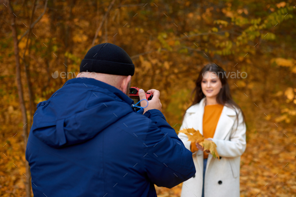 professional reportage photo shooting for social networks in fall park. focus on photographer back