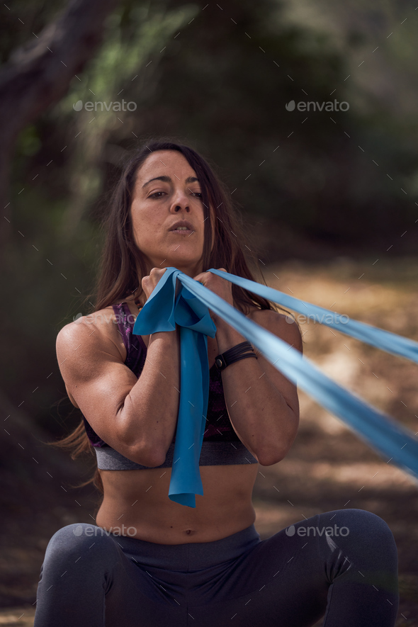 Fit lady doing exercise with resistance band in nature Stock Photo