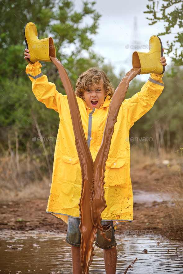 Excited boy pouring dirty water out of gumboots Stock Photo by ...