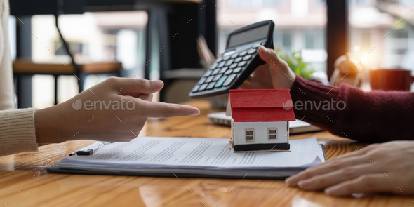 Real estate agent with calculator presenting a housing loan interest rate to client