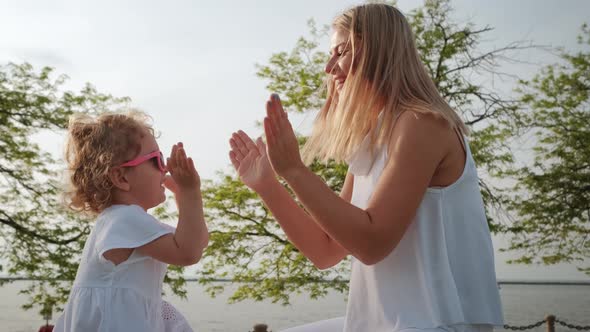 Mom and Daughter Playing Clapping Game in the Park at Sunset alt
