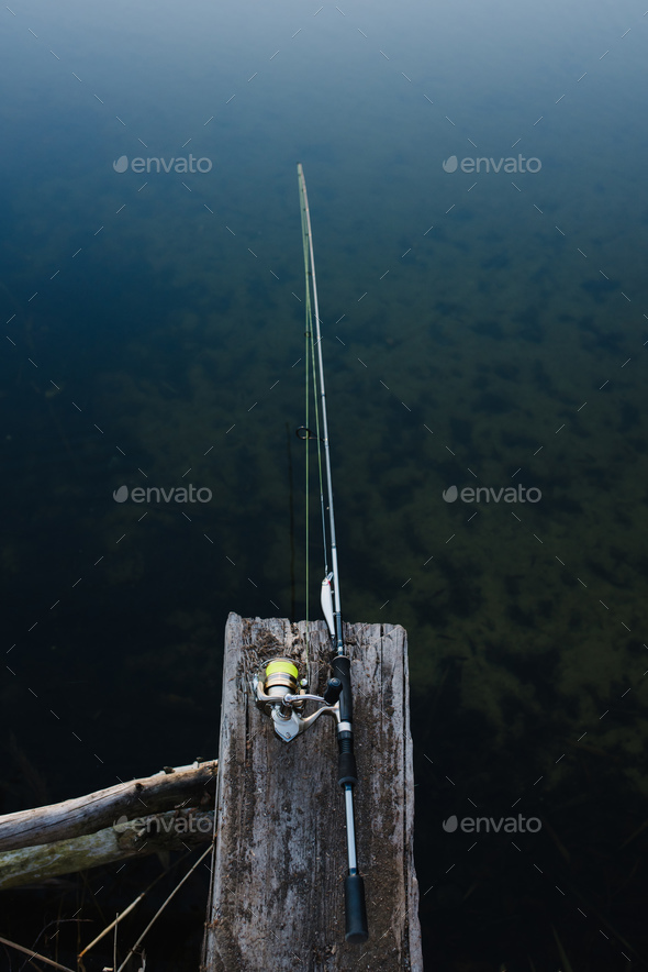 Fishing rod on a bridge on pond background. Spinning with reel on