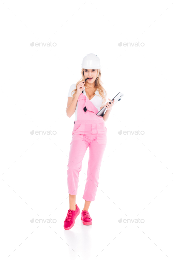 handy woman in pink overalls, hardhat with paper clipboard pen on white  background Stock Photo by LightFieldStudios