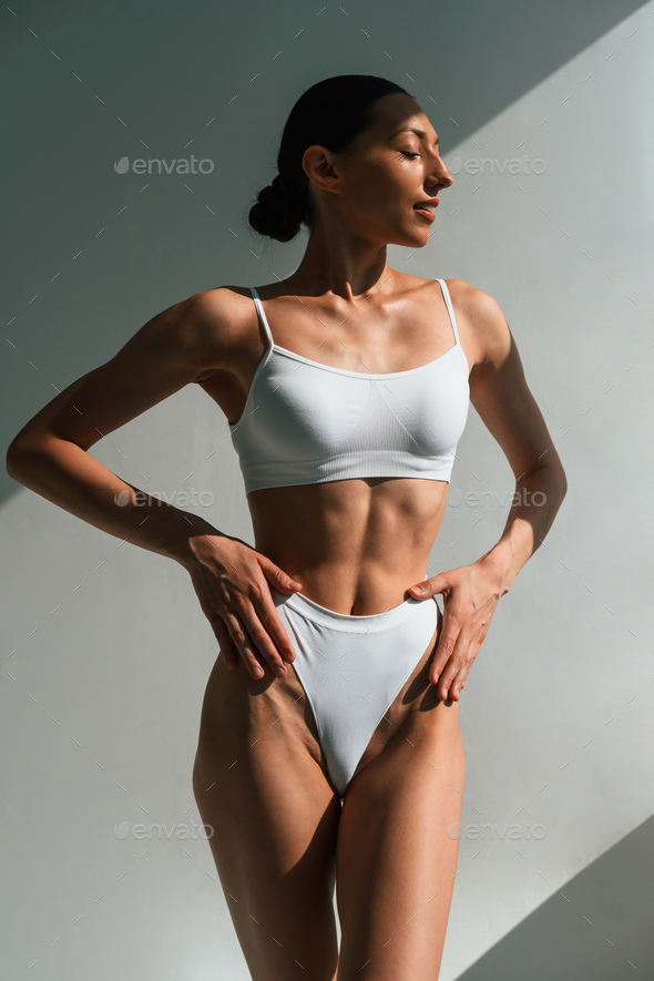Showing abs. Young woman with slim body type is in fitness clothes