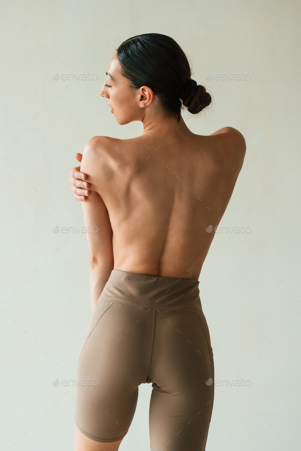 showing the spine, without bra. Young woman with slim body type is