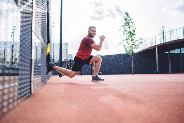 Happy man stretching leg with sling trainer Stock Photo by GaudiLab