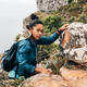 Portrait of woman hiker climbing rock and looking away. Young