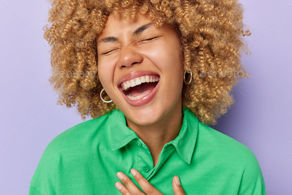 Close Up Shot Of Overjoyed Curly Haired Young Woman Keeps Eyes Closed