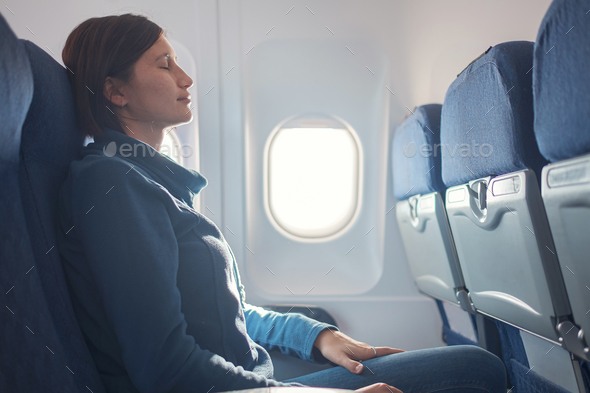 Young beautiful woman sitting at window of plane during the flight