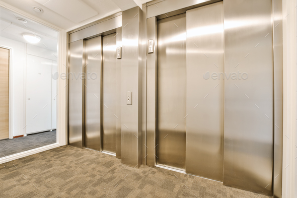 a row of stainless steel elevator doors in a hallway
