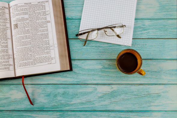 Open Holy Bible lying on wooden table in a reading with cup of coffee