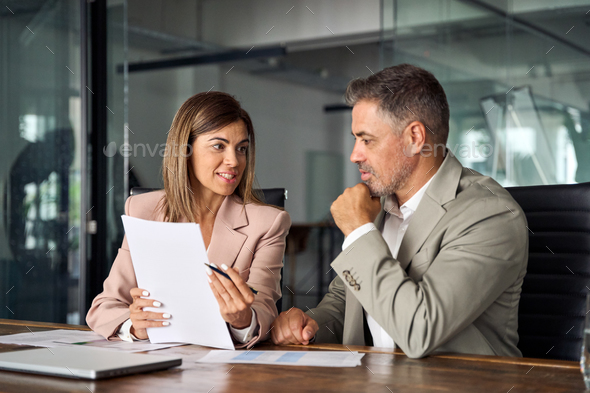 Female lawyer or bank manager consulting male client holding papers in office.