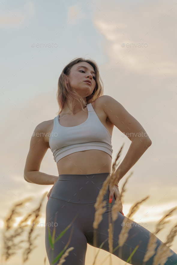 Female Fitness Trainer on the sand beach sunset background. Meditation and  harmony and balance Stock Photo by denismuse777