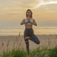 Premium Photo  Female fitness trainer on the sand beach sunset background  meditation and harmony and balance