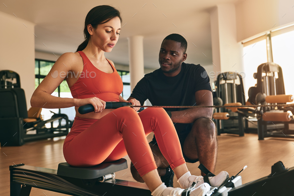 Black male trainer instructing sportswoman exercising on