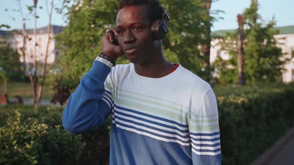 Black Young Man Listens to Music with Headphones