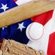 Baseball, baseball bat and baseball gloves on an American flag