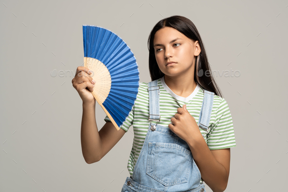 Sweaty teenage girl using paper fan suffer from heat cooling in hot summer weather