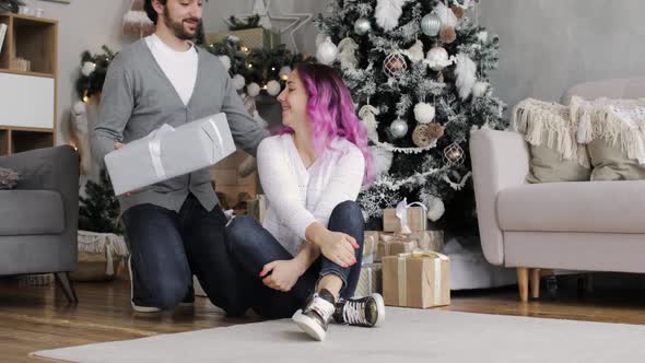 Young Man Gives a Gift To His Surprised Wife in the New Year's Interior at Home